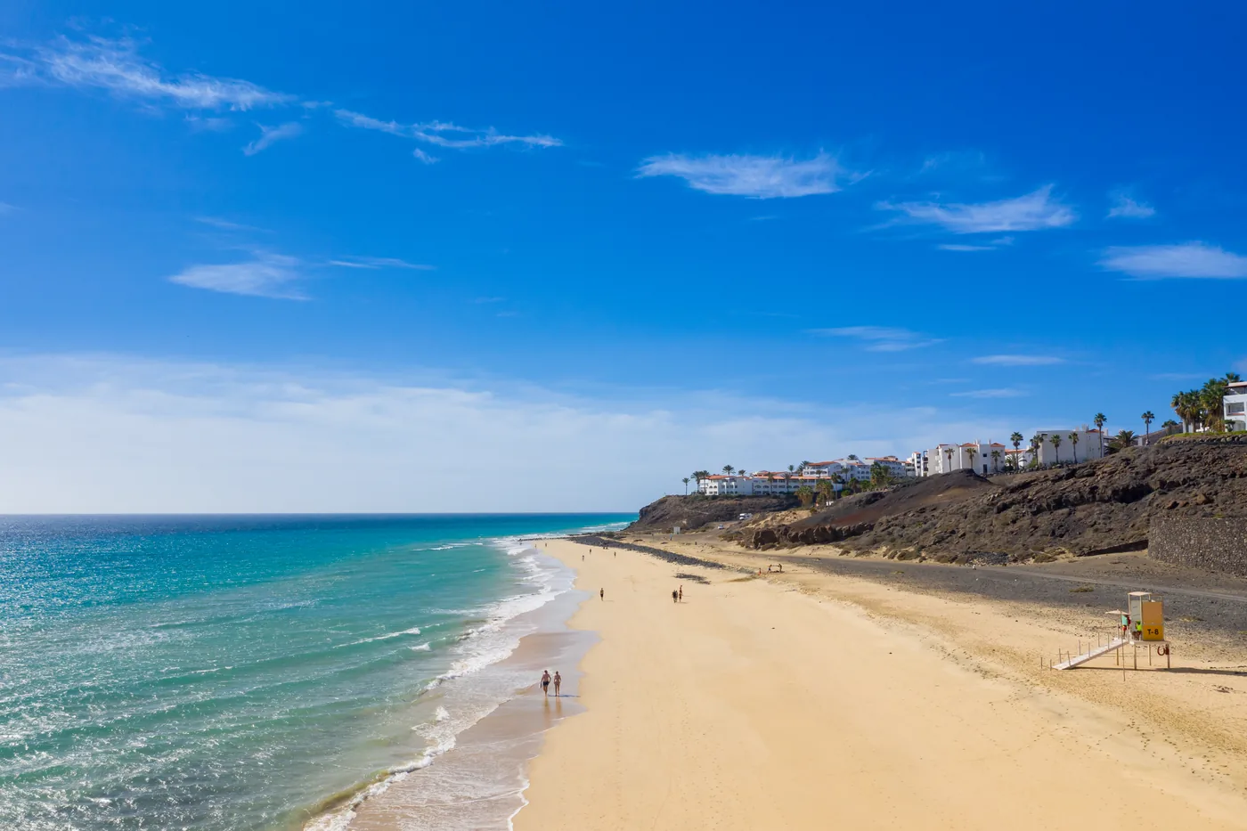 The long golden beach of Esquinzo-Butihondo with hotels on the cliffs, seen from the air from the east, Fuerteventura.