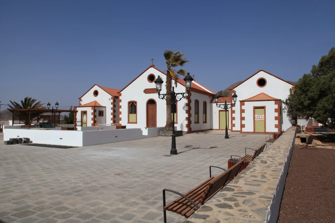 The white chapel of San Pedro de Alcántara with red-trimmed corners on a paved square in La Ampuyenta, Fuerteventura.