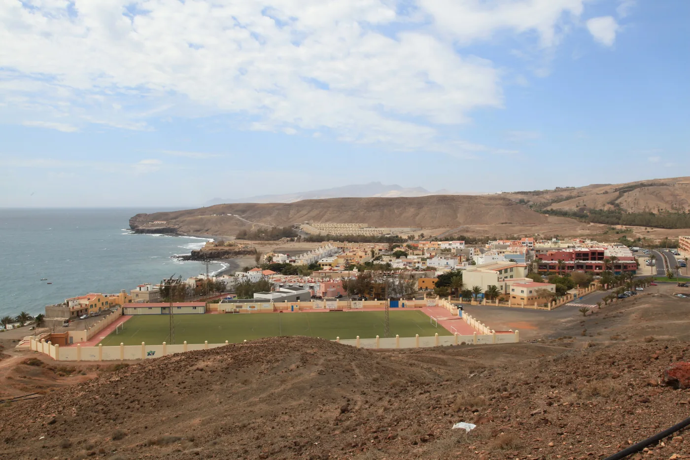 The village of La Lajita with its football pitch by the bay, coast and mountains behind, Fuerteventura.