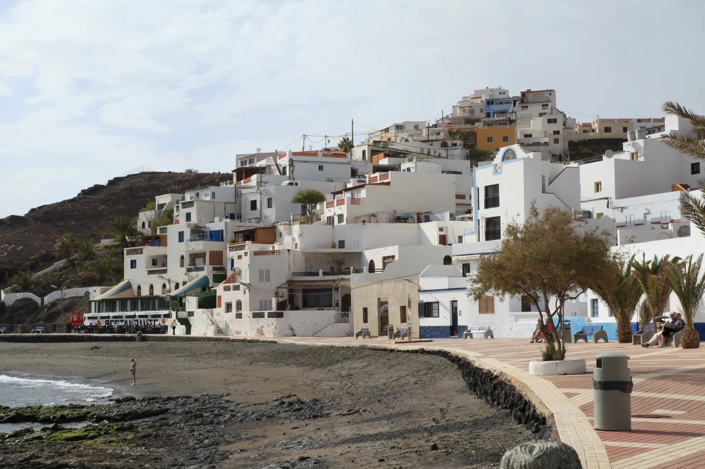 White houses of Las Playitas on the slope above the seafront promenade and the dark beach, Fuerteventura.