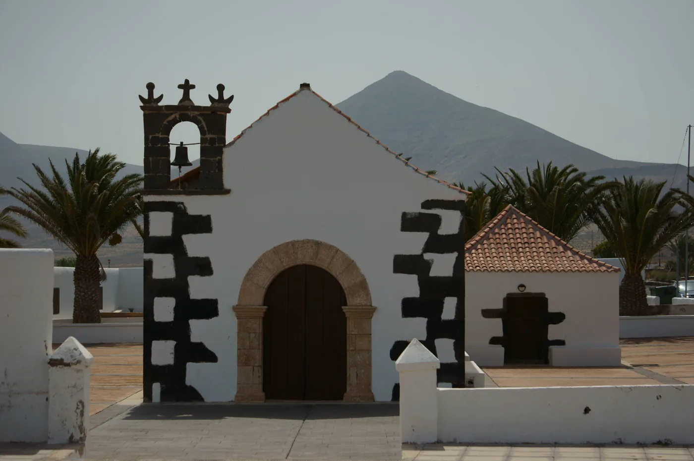 The white chapel of Tindaya with palms and mountains behind, Fuerteventura.